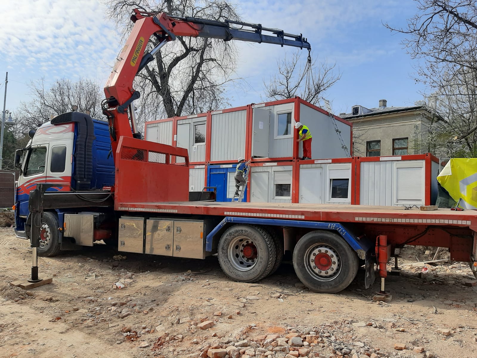 Camion cu macara manipuland un container